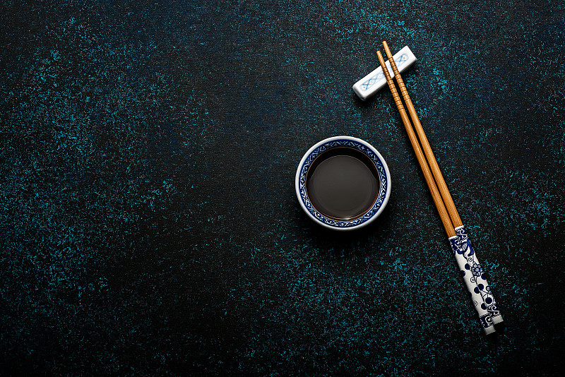 日本寿司筷子和酱油碗在蓝色的黑色石头背景图片下载