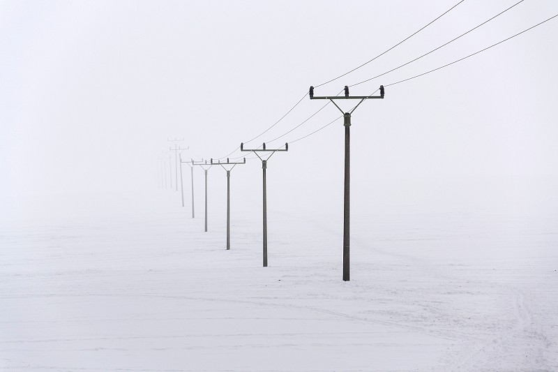 来自配电站的电塔消失在浓雾中，冬天寒冷刺骨……图片素材