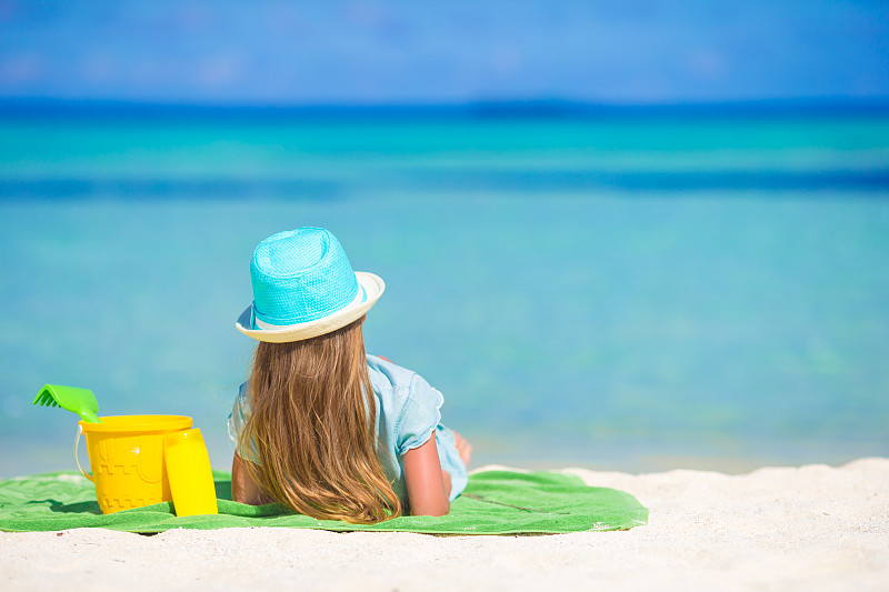 可爱的小女孩戴着帽子在暑假的海滩上图片素材