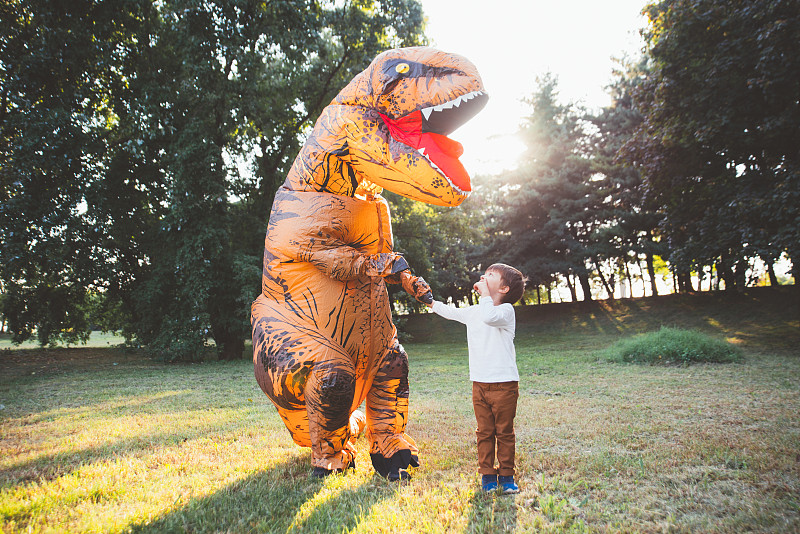 爸爸和儿子在公园里玩，穿着恐龙服装图片素材