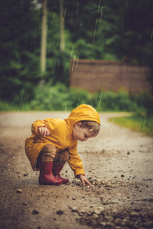 小男孩在雨中在马路上玩耍图片素材