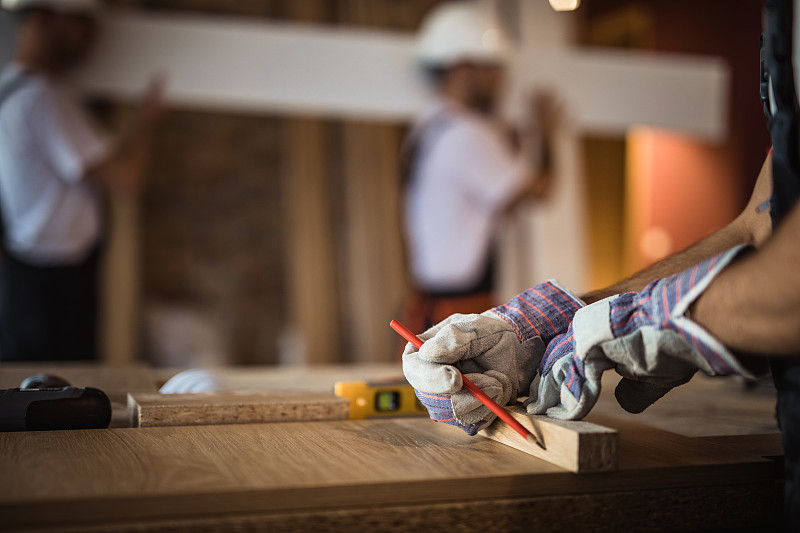 在家庭装修过程中，建筑工人在木板上绘制测量图的特写。图片下载