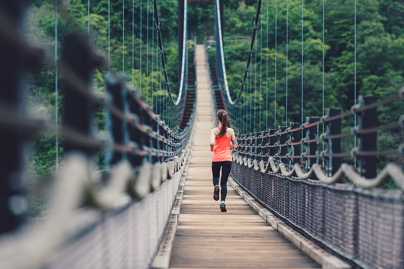 在桥边慢跑的女运动员图片下载
