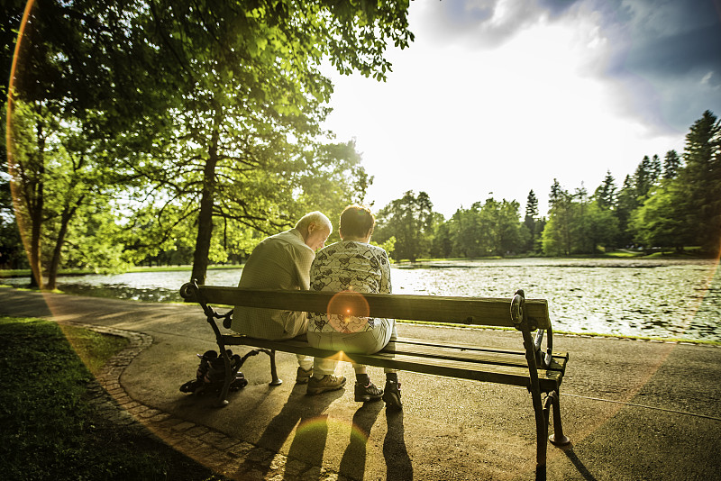 一对老年夫妇坐在公园湖边的长椅上图片下载