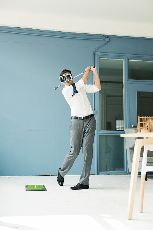 商人戴着VR眼镜在办公室打高尔夫图片下载