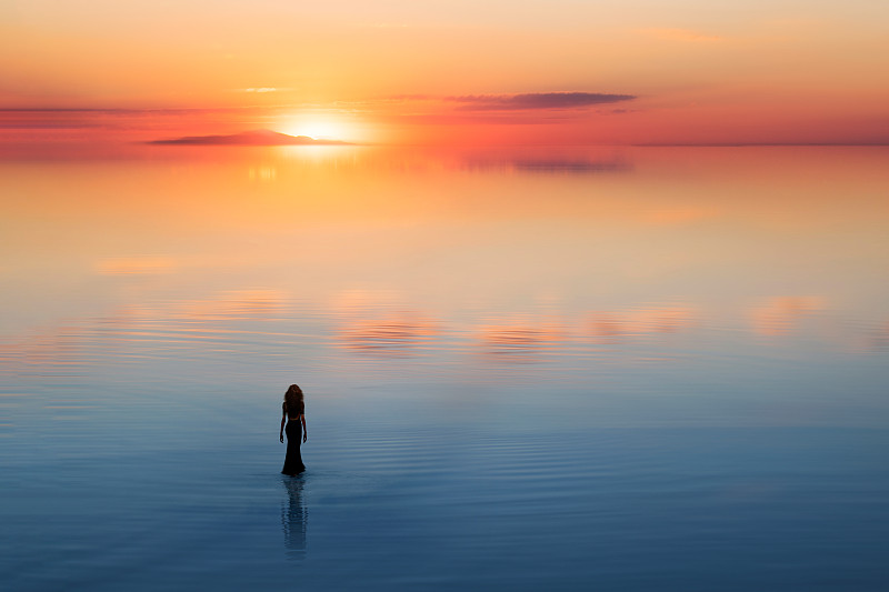 孤独的女人在水面上向着太阳走去图片下载