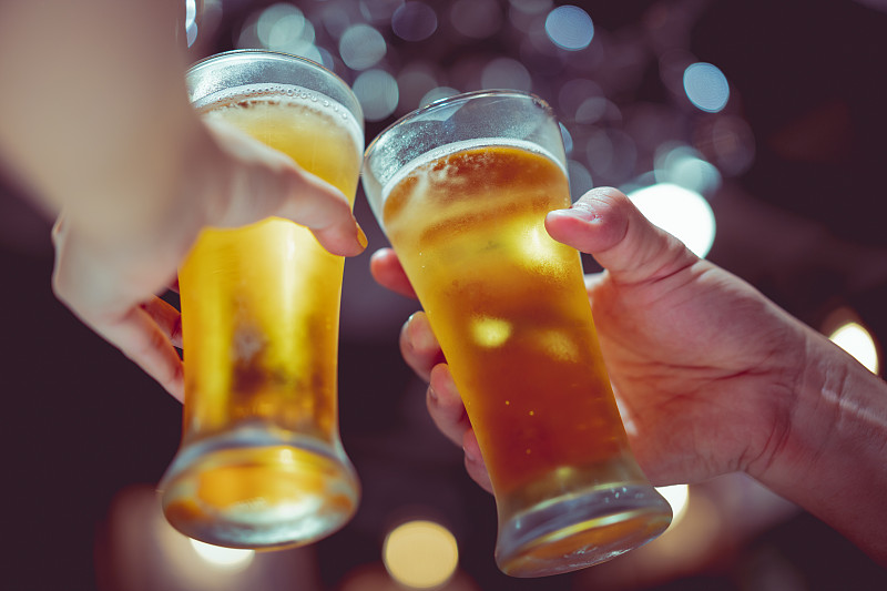 在酒吧里，人们向啤酒杯祝酒的手被剪断了图片素材