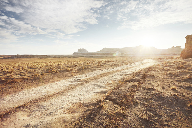 在干旱的沙漠景观土路与遥远的悬崖和阳光图片下载