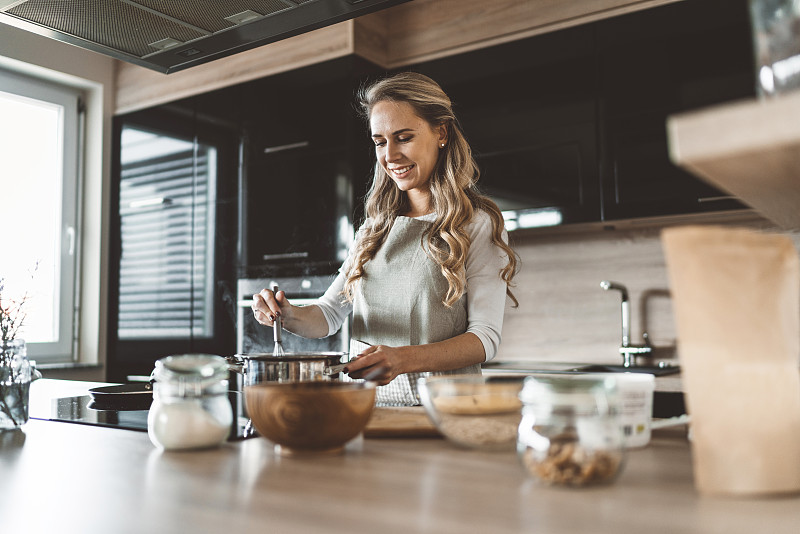 一个金发女人在现代化的厨房里做饭图片下载