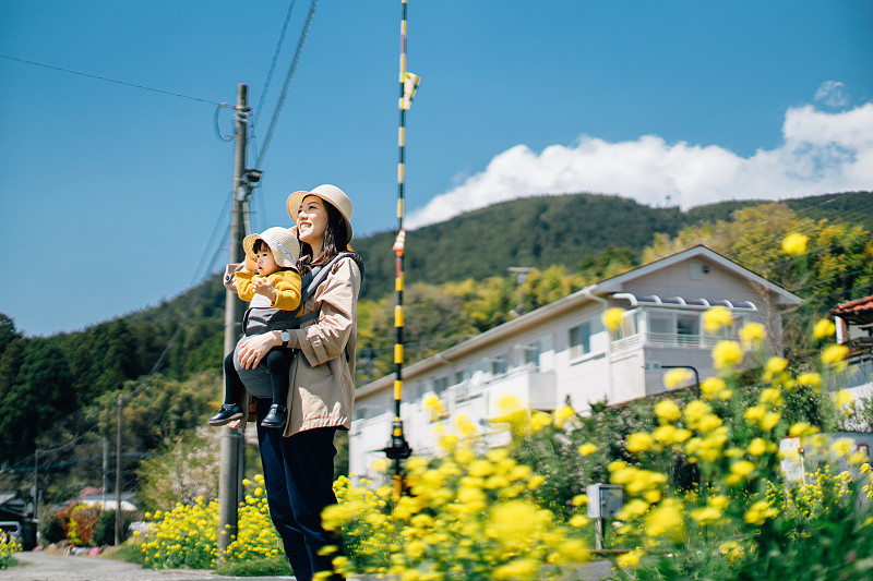 快乐的母亲和女儿在大自然中旅行，在油菜地上，在蓝天下散步图片下载
