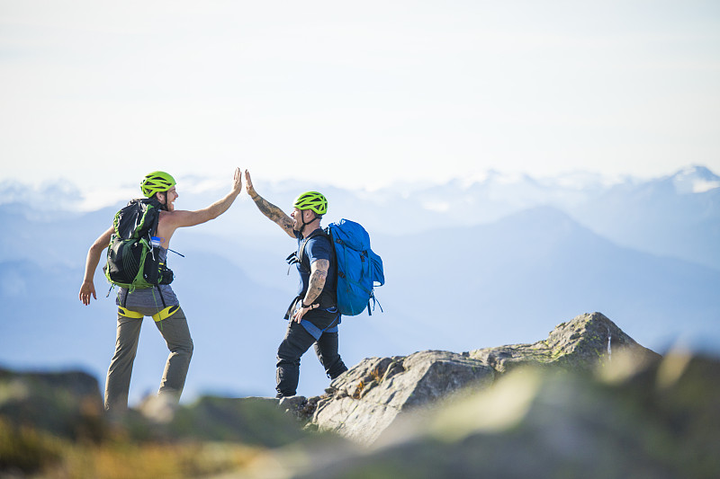 两名登山者在加拿大公元前道格拉斯峰的山顶击掌。图片素材