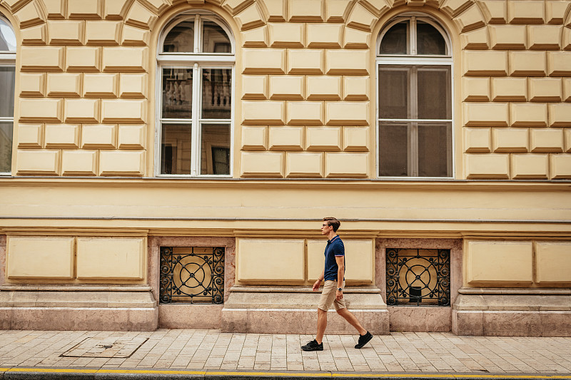 游客经过布达佩斯第八区历史悠久的黄色建筑图片下载