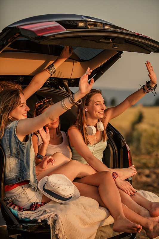 快乐的年轻女性在她们的露营之旅在远处挥手图片素材