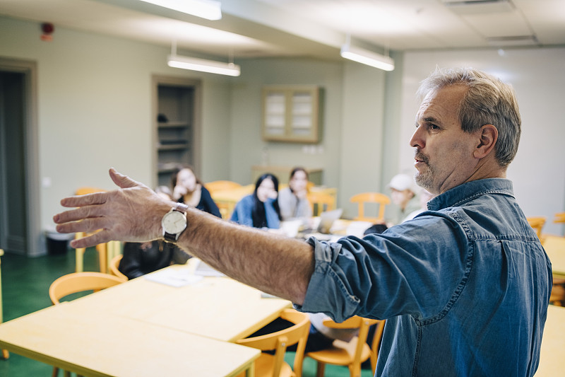 高级男老师在课堂上一边讲课一边打手势图片素材