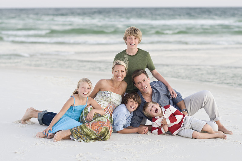 三个男孩(10- 12,7 -9)和女孩(7-9)在沙滩上摆姿势拍照，这是一个幸福的家庭图片素材