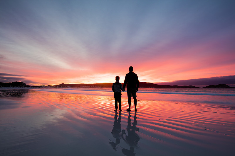一个父亲和儿子的剪影在日落海滩上牵手，西澳大利亚，澳大利亚图片下载