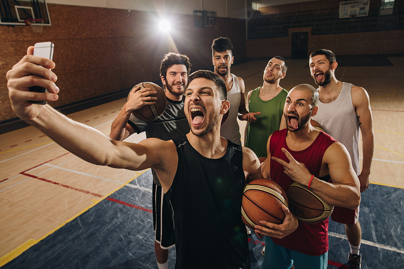 一大群篮球运动员在球场上自拍时做鬼脸。图片下载