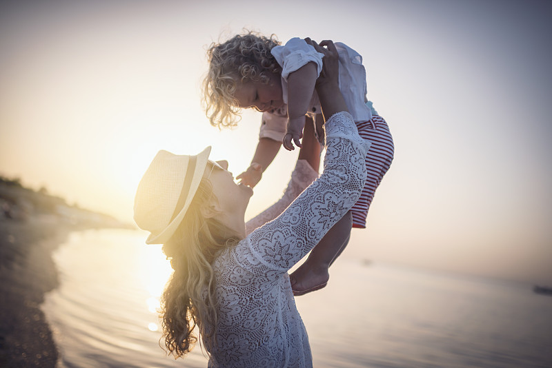 日出时分，母亲和儿子在海滩上图片下载
