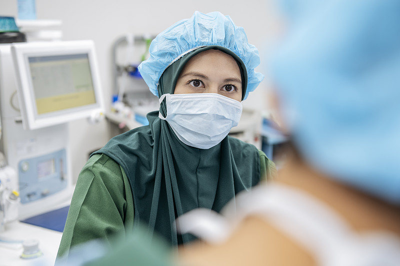 马来西亚医生戴着外科口罩，表情严肃图片素材