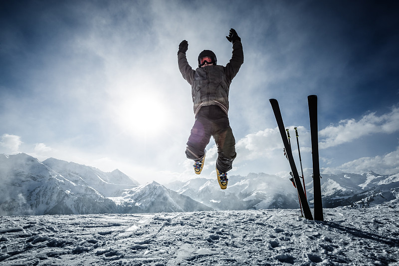 快乐的高山滑雪者在顶部的空中跳跃图片下载