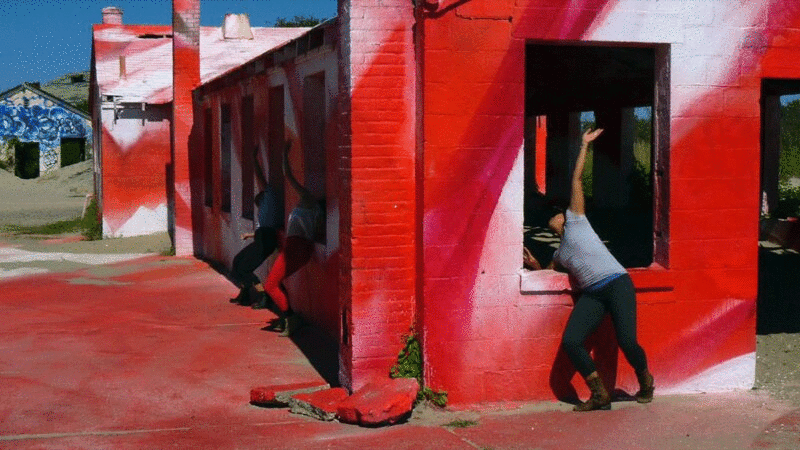 三位现代舞演员在排练中对着红色建筑跳舞图片下载