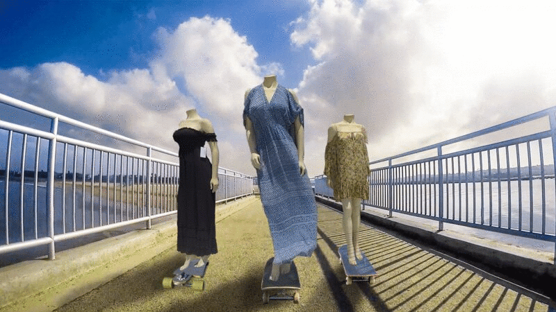 三个女性人体模型骑着滑板沿着码头，他们的衣服在风中吹图片下载