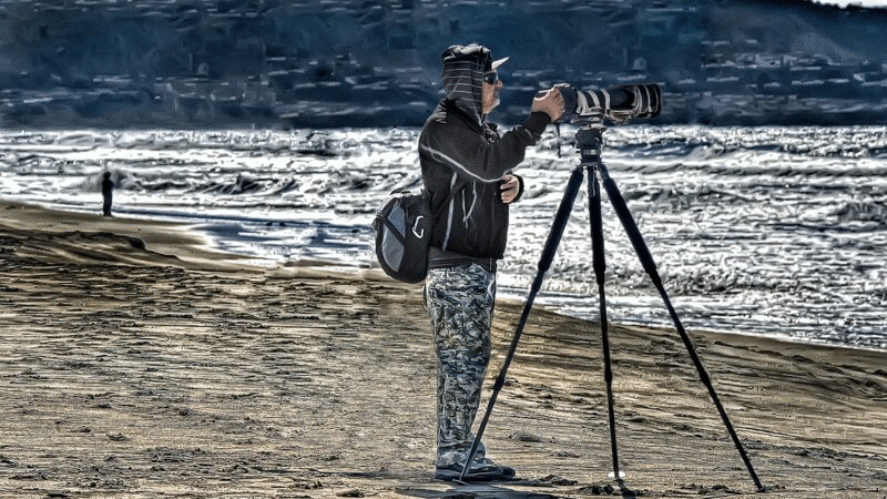 摄影师瞄准相机与长焦镜头在海滩图片下载