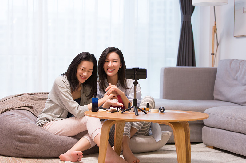 两个年轻女闺密在起居室化妆美容护肤做网络直播图片下载