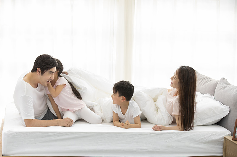 快乐的年轻家庭在床上图片下载