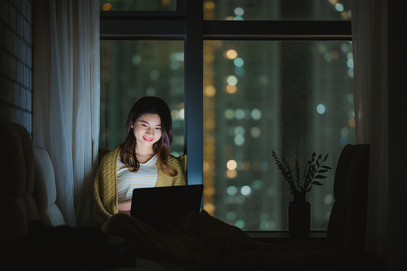 亚洲年轻女孩夜晚在家使用笔记本电脑图片素材