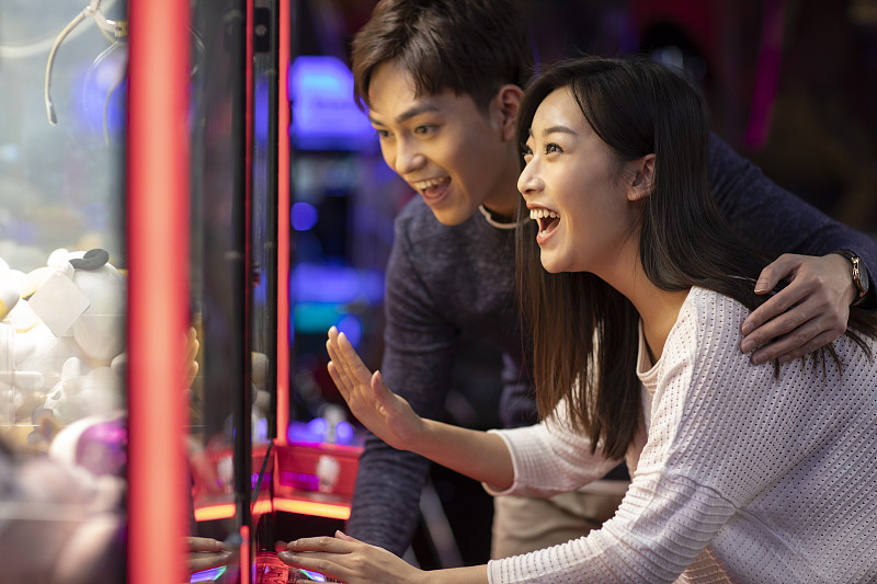 快乐的年轻情侣玩街机游戏图片下载