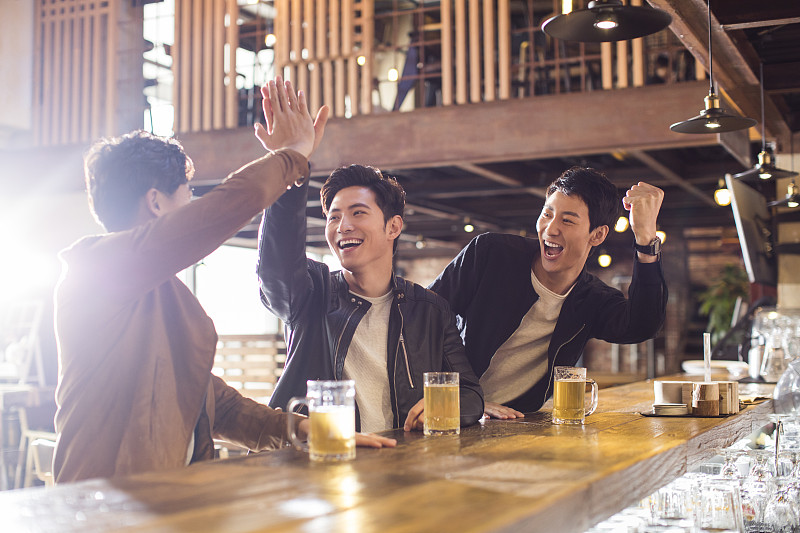 快乐的年轻男士在酒吧喝酒欢呼图片素材