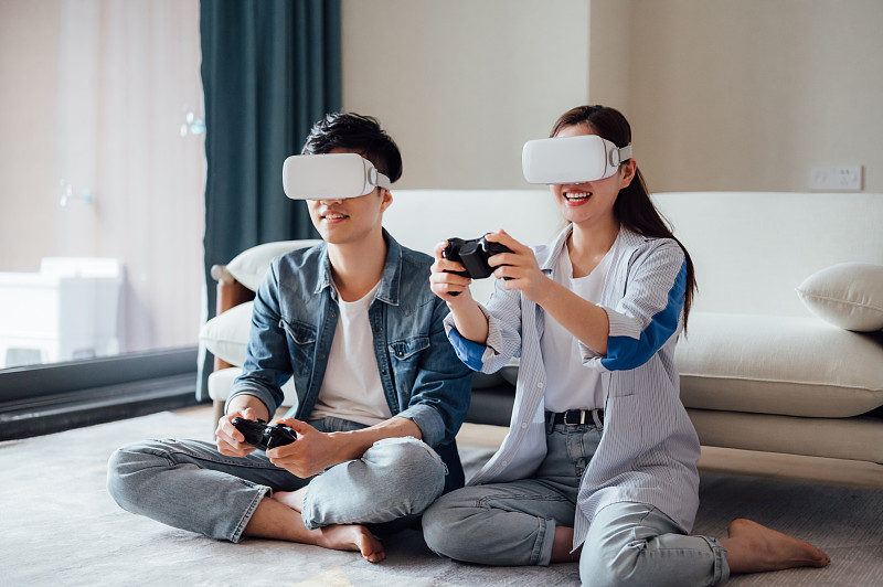 亚洲年轻情侣在家戴VR眼镜打游戏图片素材