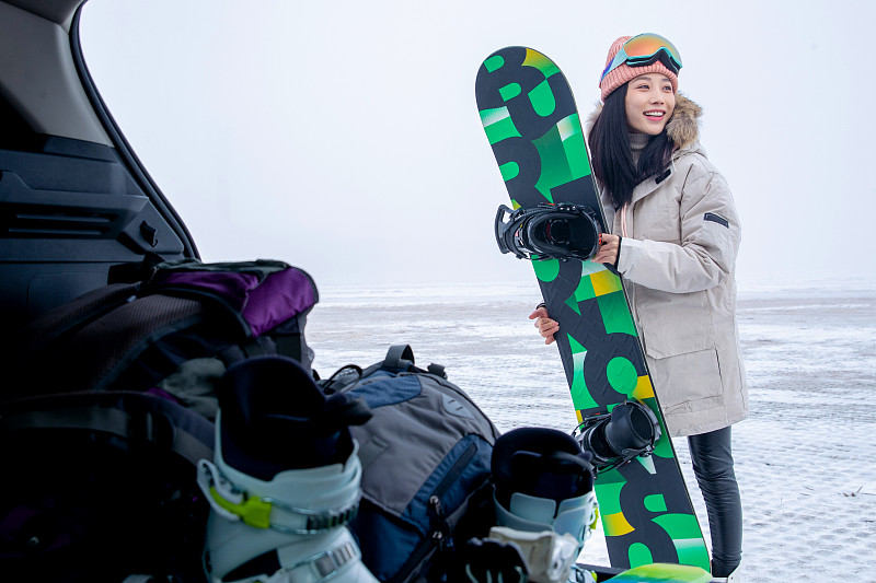 青年女人从后备箱拿单板滑雪板图片下载