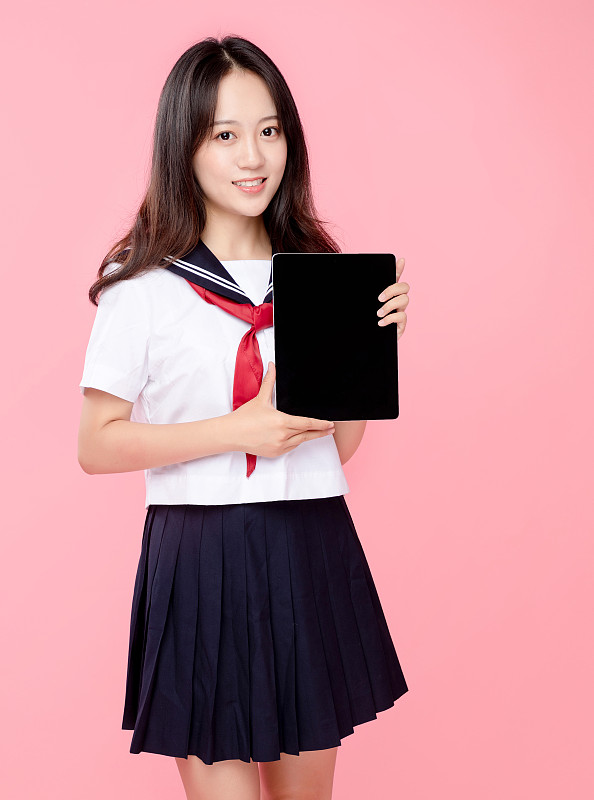 粉红色背景里，拿着平板电脑的可爱女学生图片下载