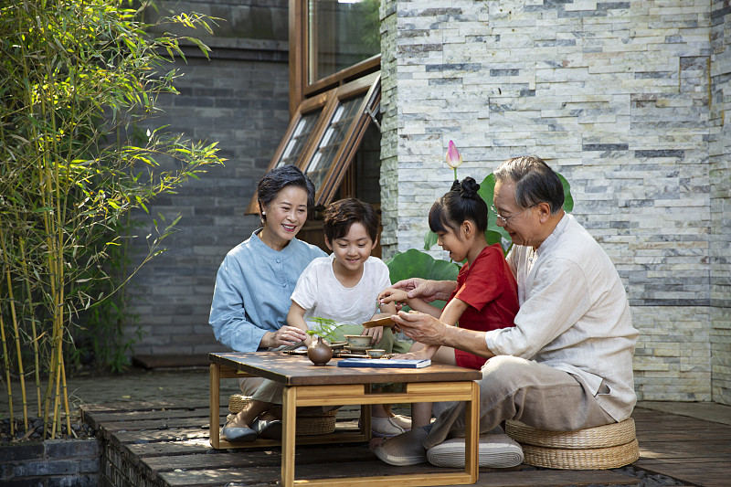 爷爷、奶奶教孙女、孙子两个孩子在庭院学习中国茶道图片素材