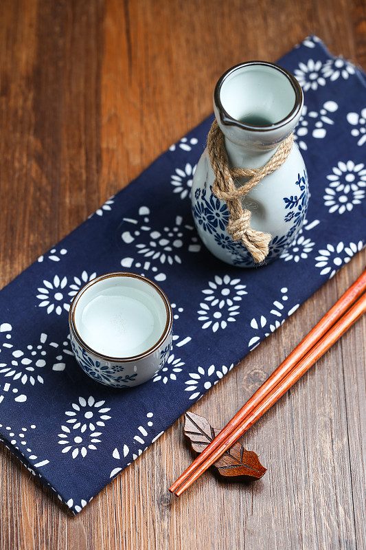 日本清酒白酒酒壶酒杯酒具放在蓝花布上图片下载