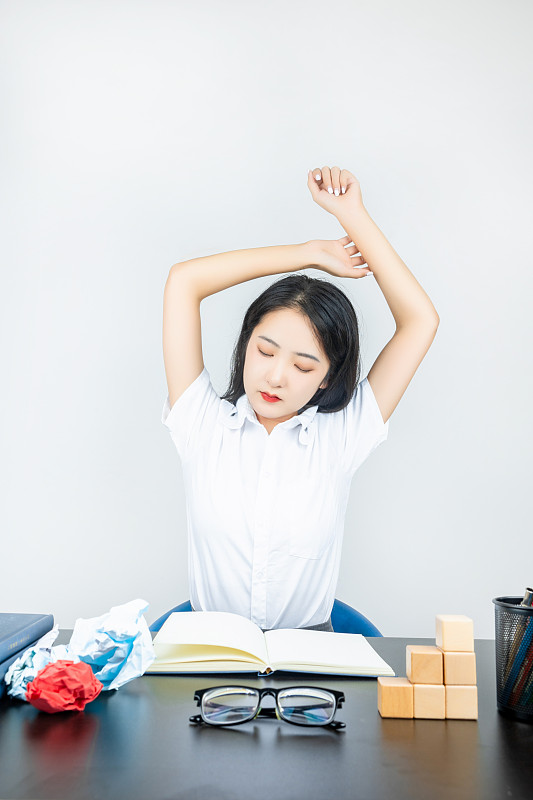 亚洲美女大学生在书桌上学习睡觉伸懒腰图片下载