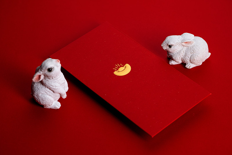 在红色背景里的两个兔子摆件和红包图片下载