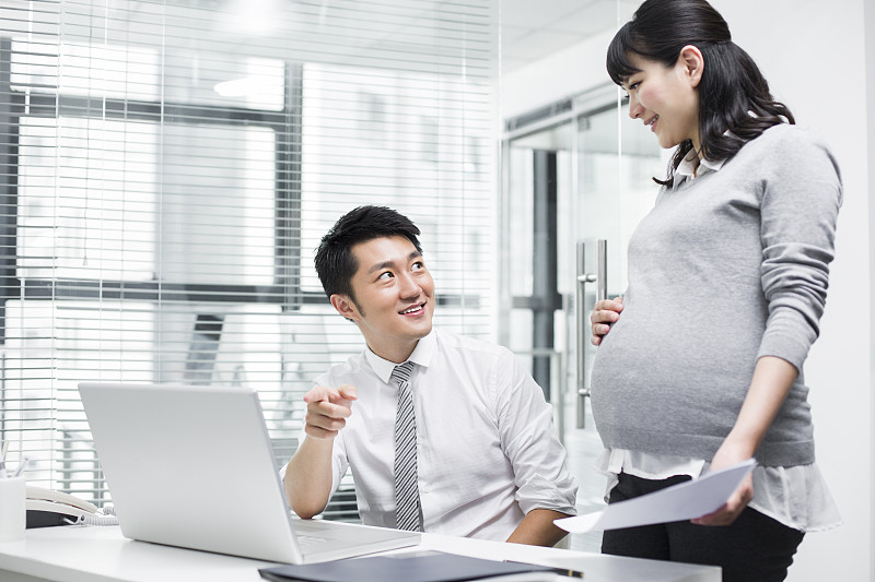 怀孕的商务女士和同事一起工作图片下载