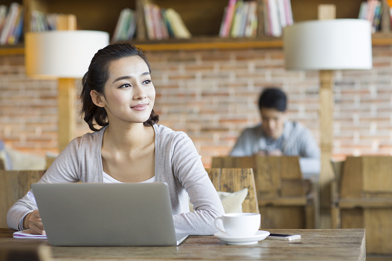 年轻女子在咖啡馆使用笔记本电脑图片下载