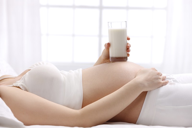 孕妇拿着牛奶放在肚子上图片下载