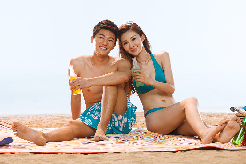 海滩上喝饮料的浪漫情侣图片素材