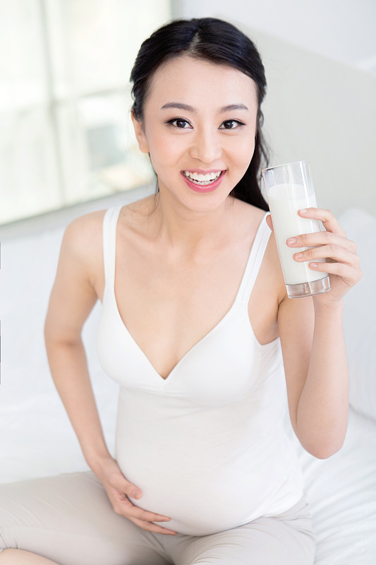坐在床上喝牛奶的孕妇图片下载