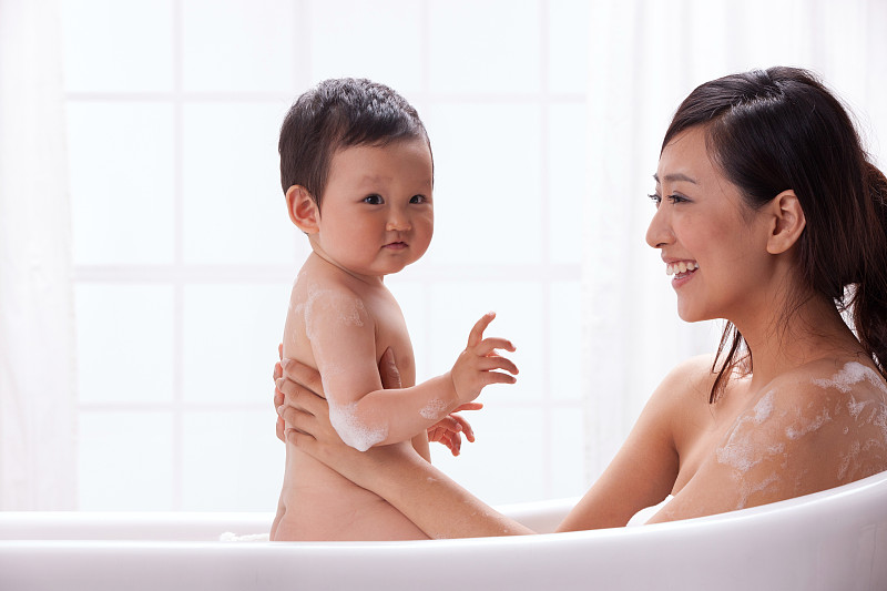 母亲和婴儿坐在浴缸中洗澡图片下载