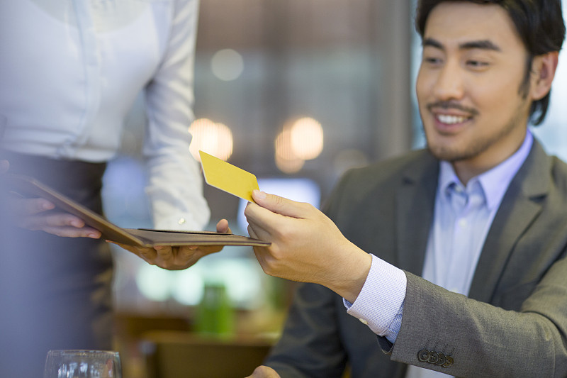 商务男士在餐馆使用信用卡结账图片下载