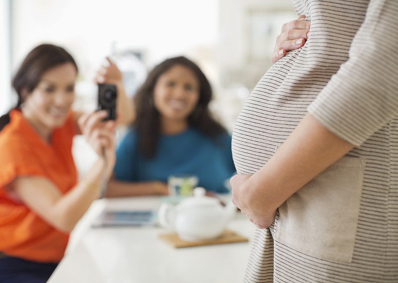 一个女人在给怀孕的朋友拍肚子图片素材