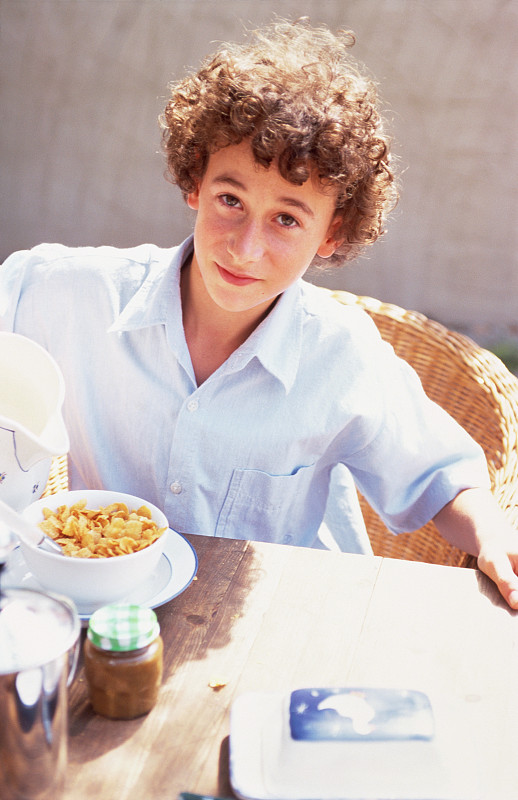 男孩在阳光露台上吃早餐图片下载