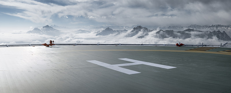 雪山云海背景的逆光下的直升机停机坪图片下载