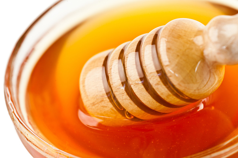 蜂蜜舀出一个碗在白色的背景图片下载